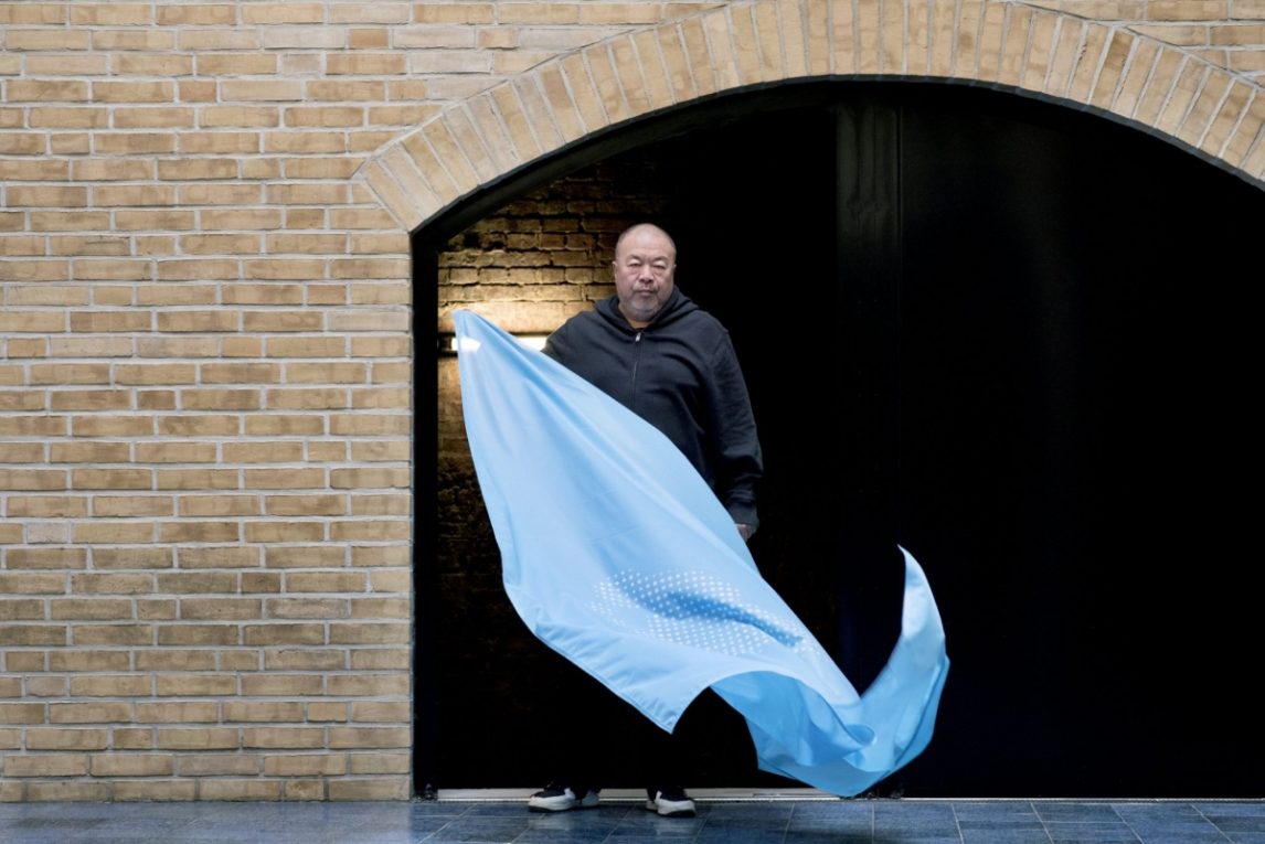 Ai Wei Wei holding a pale blue flag