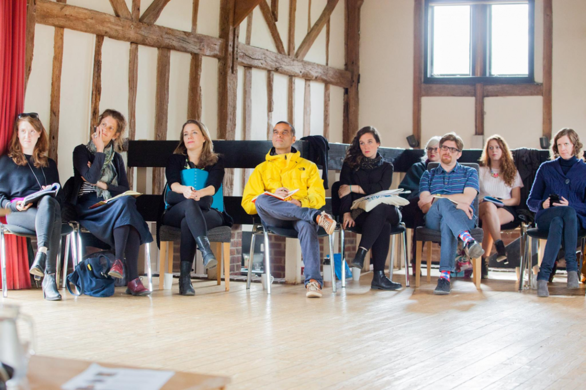 A group of people sat in a row listening to a speaker who is out of shot
