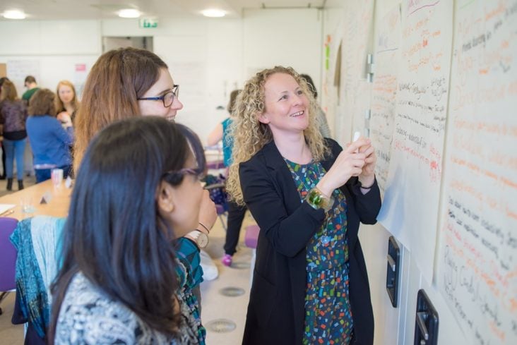 Three people writing on a white board