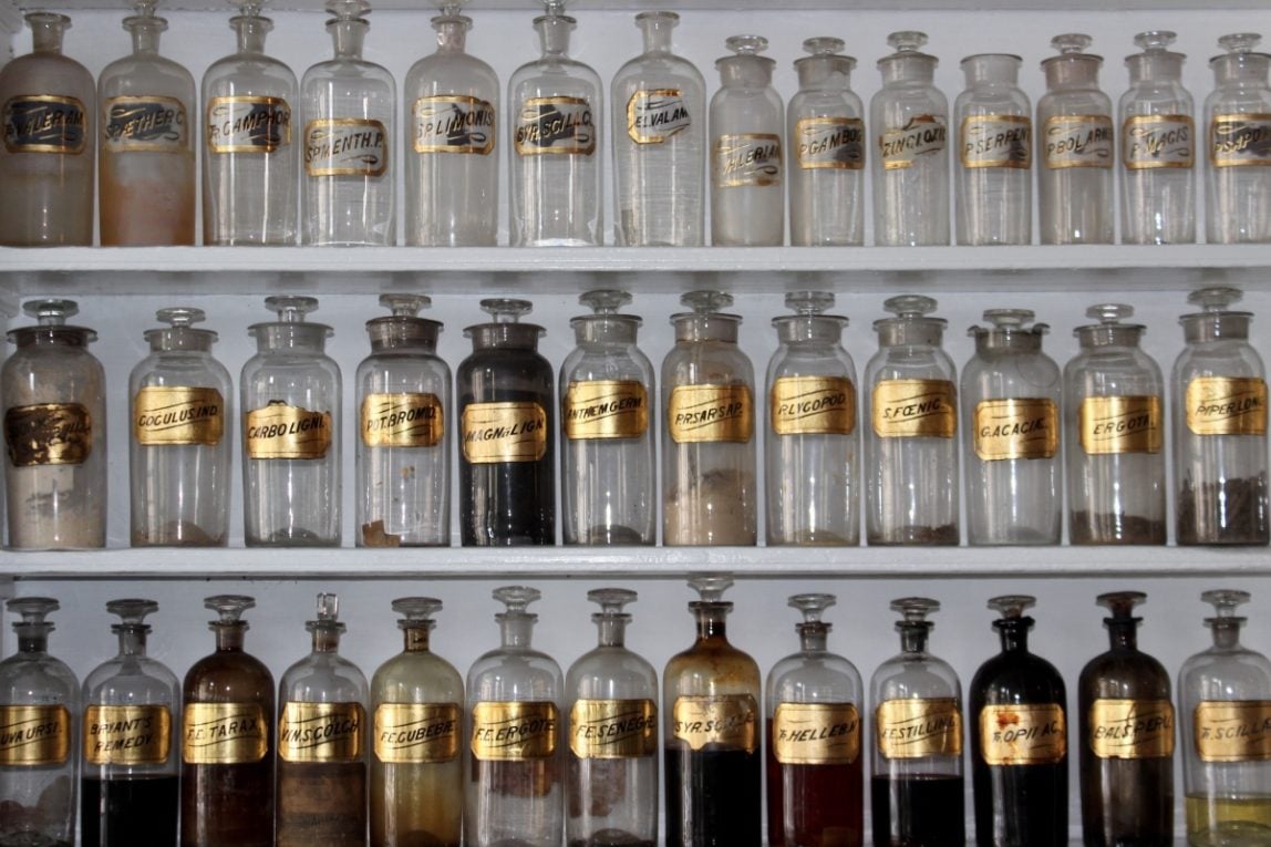 Three rows of old fashioned medical jars, some are empty and some have different substances in