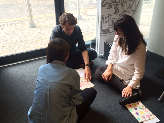 Three people sat on the floor working on a poster