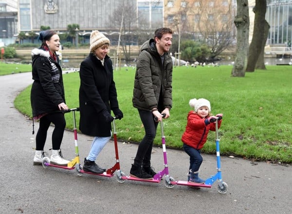 Three people and child on a four connected scooters