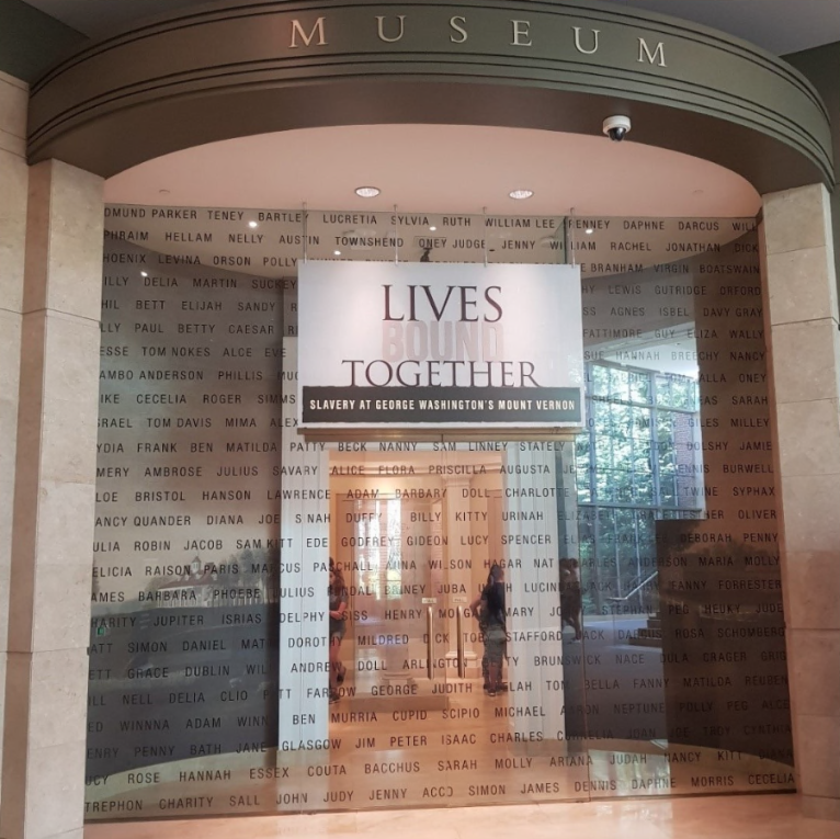 An image of a museum, the sign reads 'Lives Bound Together, Slavery at George Washington's Mount Vernon'