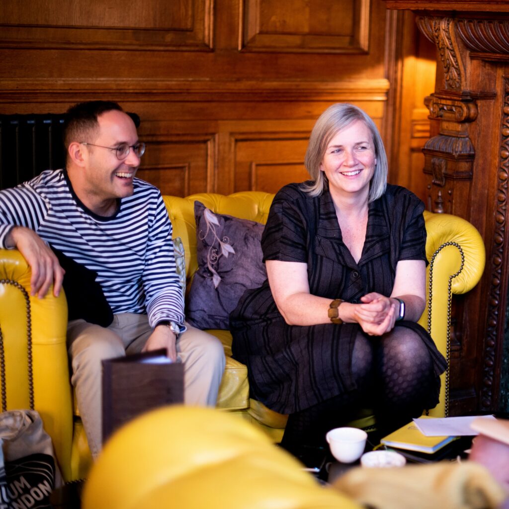 Two people sitting on a yellow sofa laughing