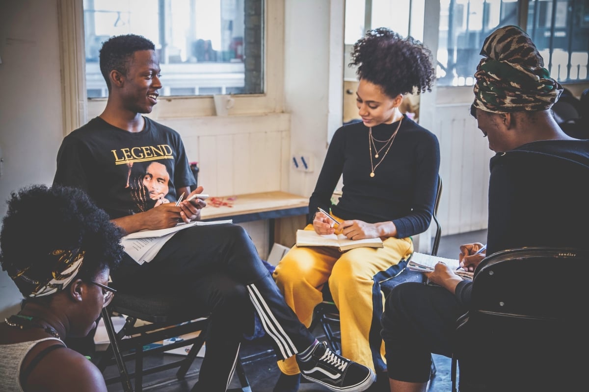 Four people sitting talking and taking notes. 