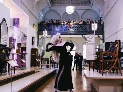 A drag queen wearing a long black dress and performing for a crowd