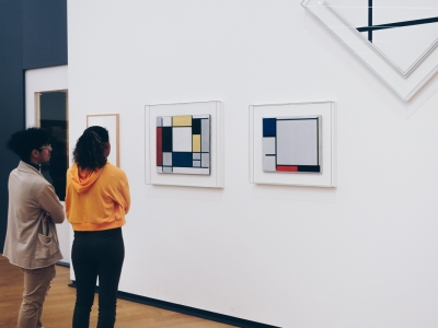 Two people in a gallery looking at a series of Mondrian paintings