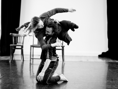 To dancers performing a lift, there are three empty chairs behind them