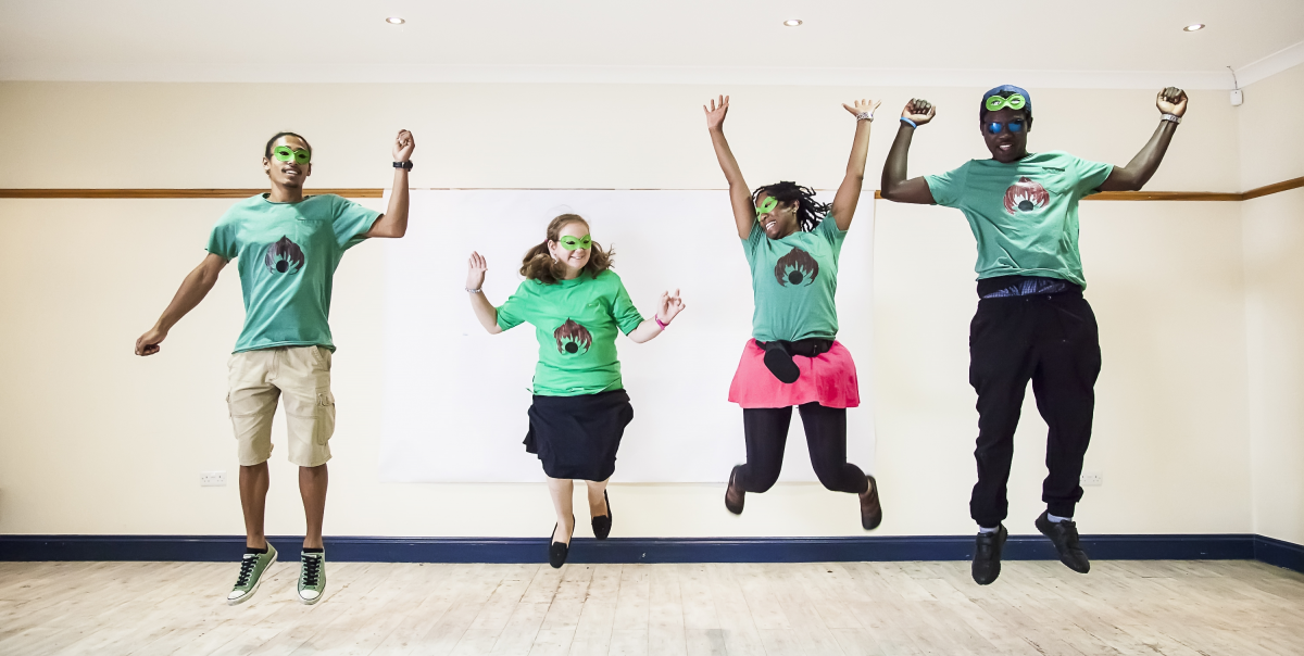 Four people dressed as super heroes jumping in a studio