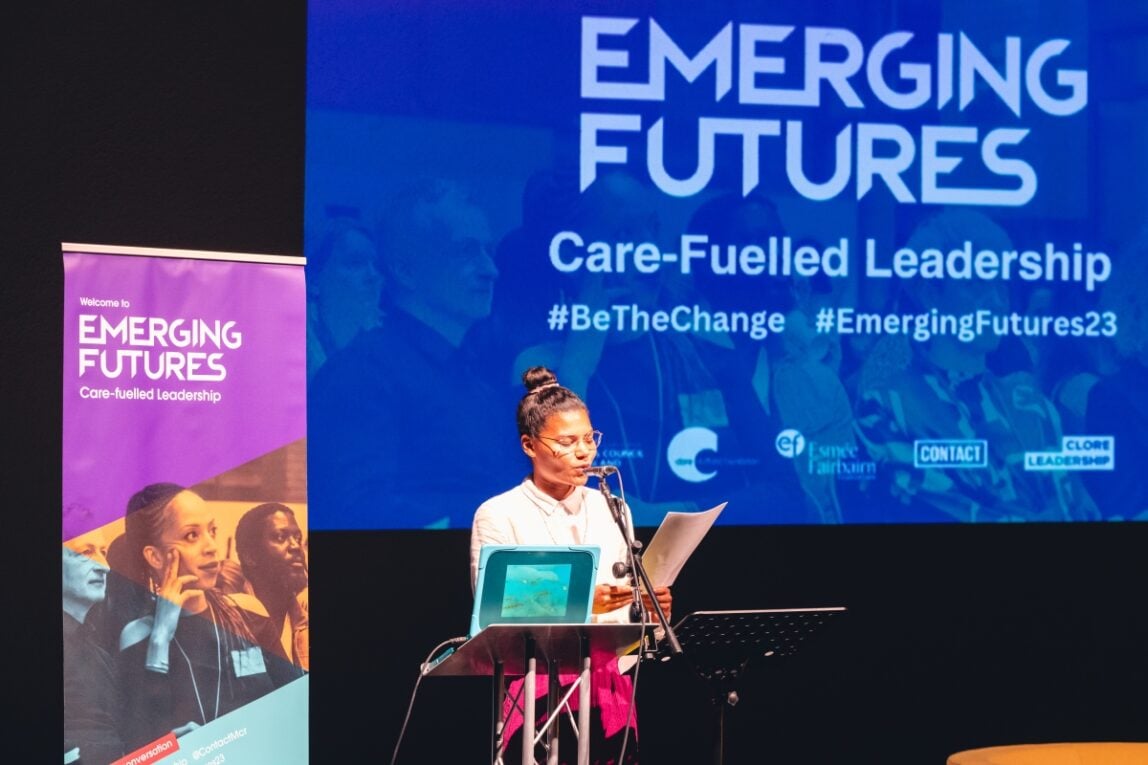 Ella Otowemo reading a poem on stage at the Emerging Futures 2023 conference