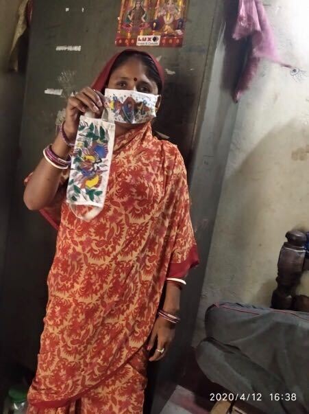 A person wearing a face mask holds out another face mask