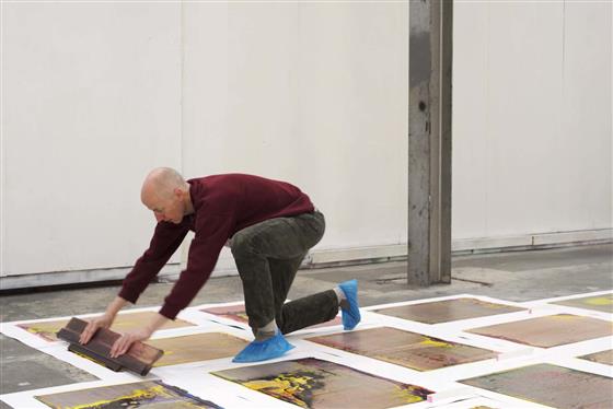 A person screen printing on the floor of a studio