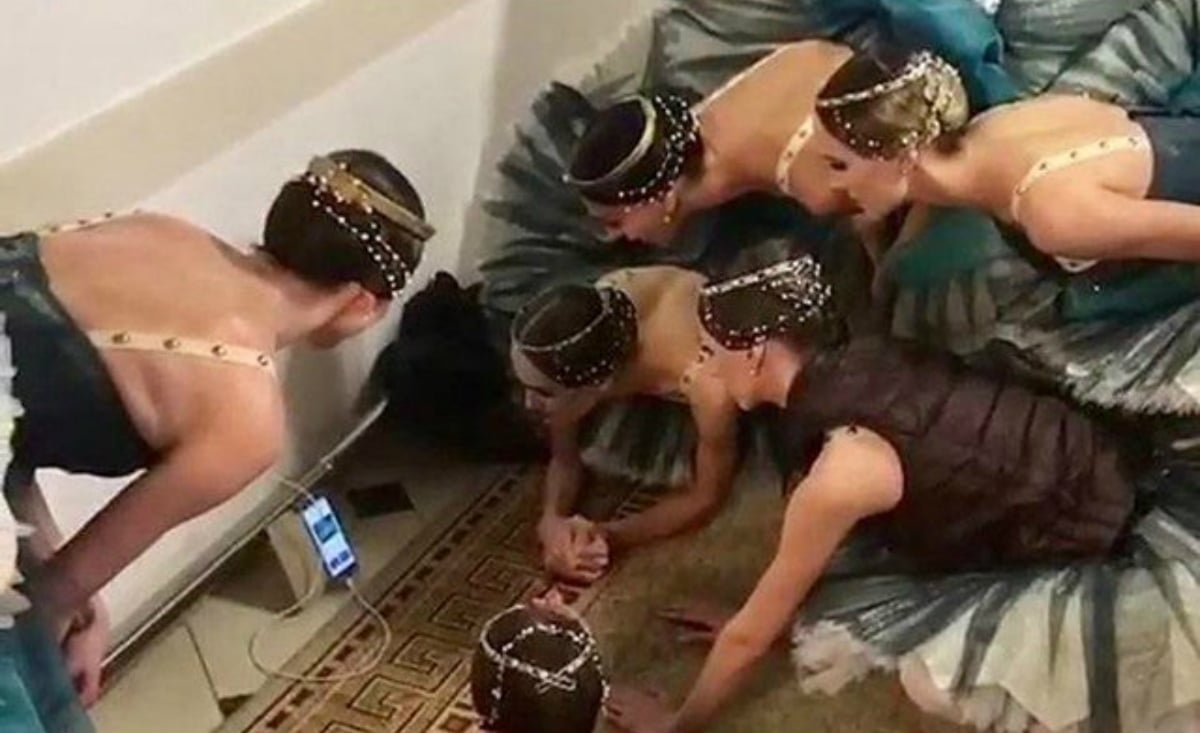 Ballerina's watching football on a mobile phone. 