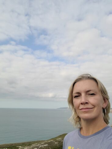 A headshot of Katy Edmunds stood in front of the sea