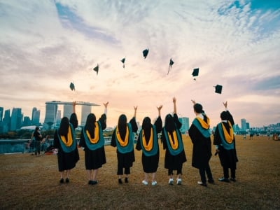 A group of graduates photographed from behind, they are throwing their hats in the air