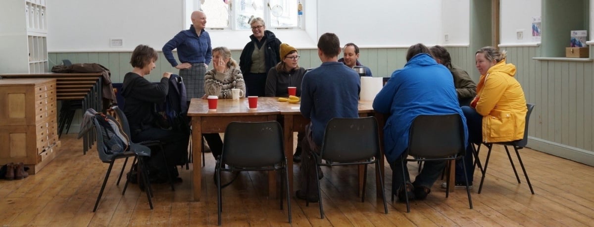 Peak artist network meeting, Black Mountains, Wales A group of people sitting around a table in a community centre.