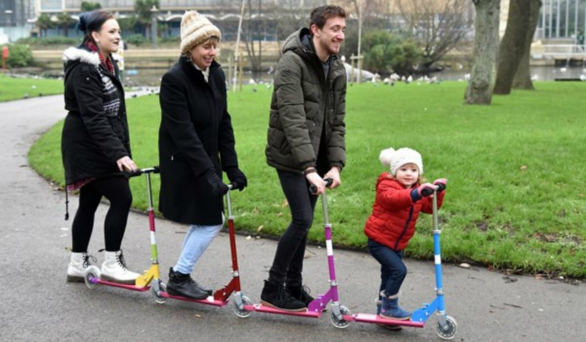 Three adults and a child on scooters