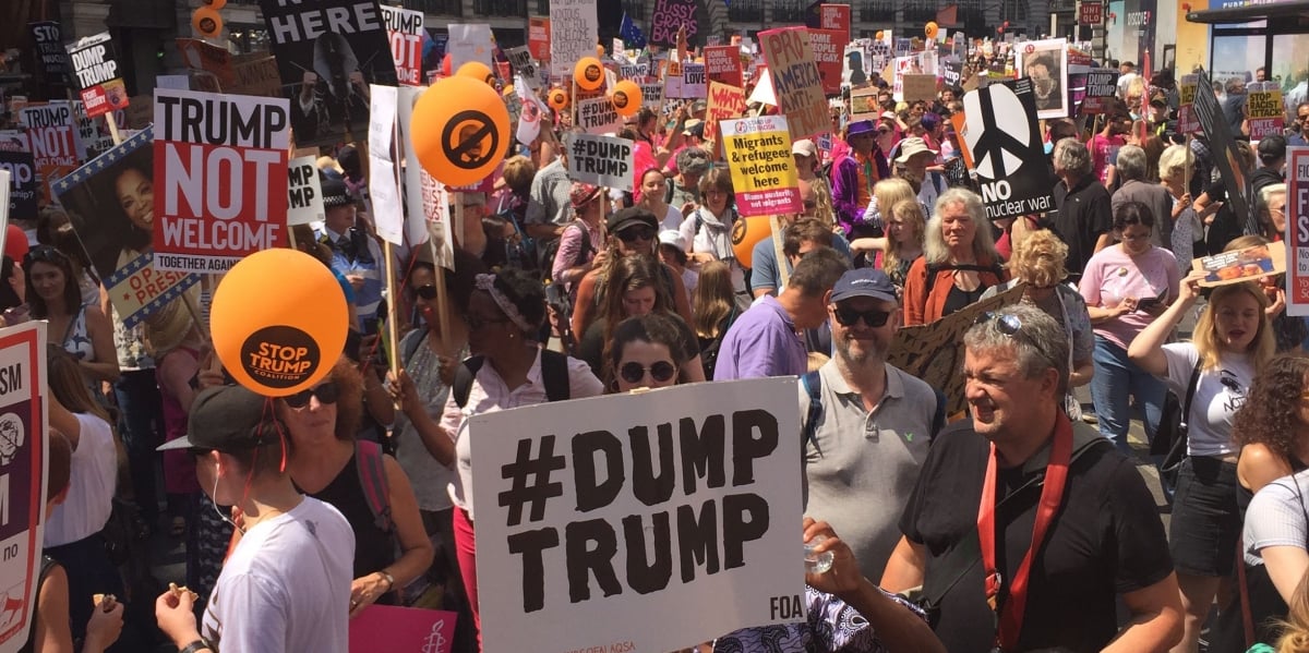 An crowd at an anti-trump rally holding signed and balloons