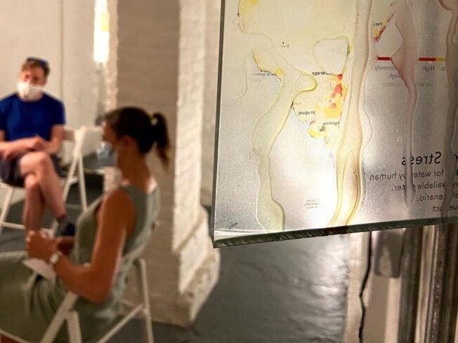 Two people sat on chairs socially distanced, wearing masks