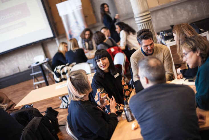 A group of cultural leaders, in discussion, seated at tables at Battersea Arts Centre