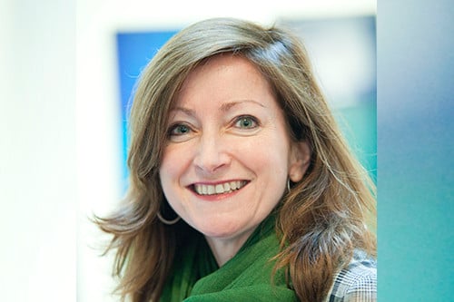 Headshot of Sally Bacon smiling into the camera wearing a green scarf