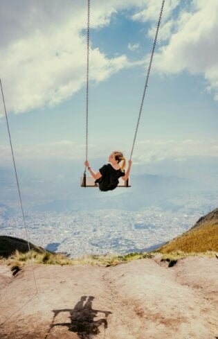Woman on a swing, swinging high about a city