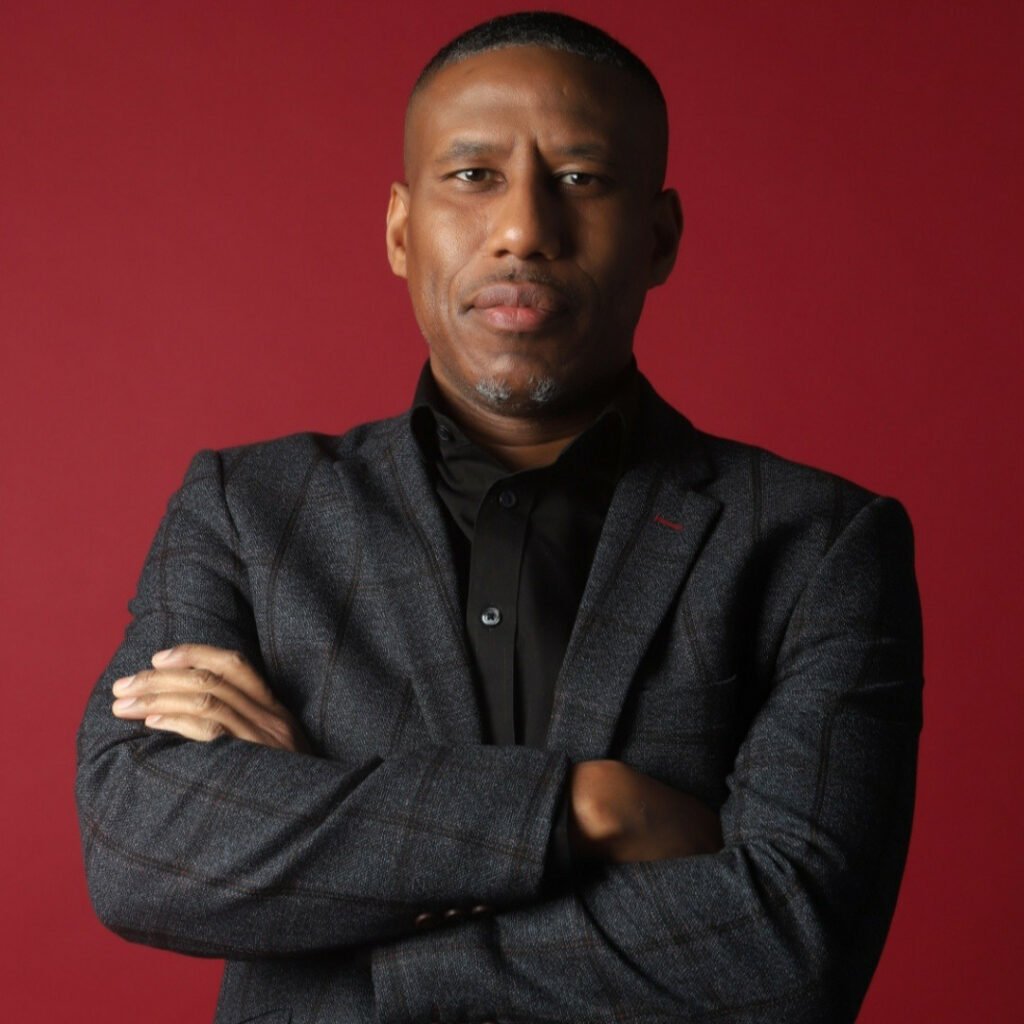 Headshot of Andrew Morris, he is wearing a suit and has his arms crossed