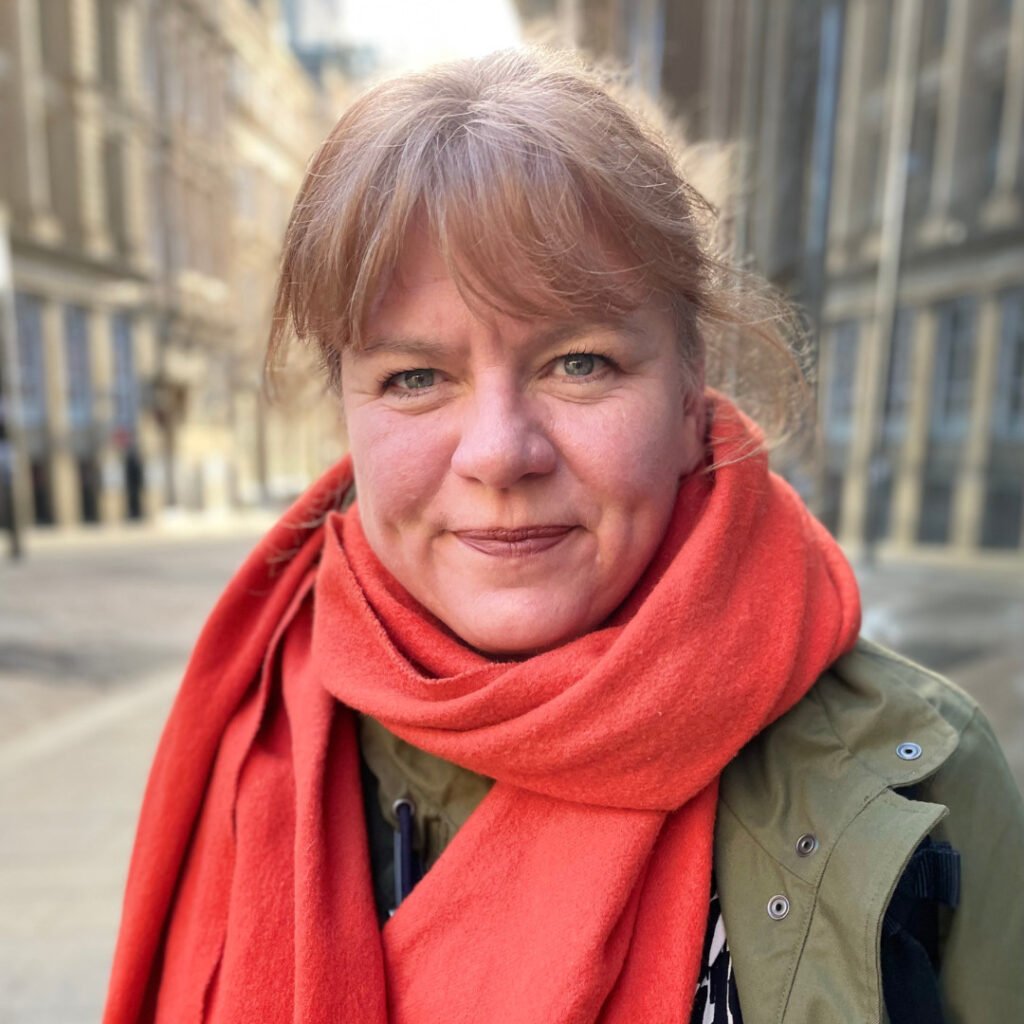 Headshot of Amanda Smethurst, she is wearing a bright red scarf 
