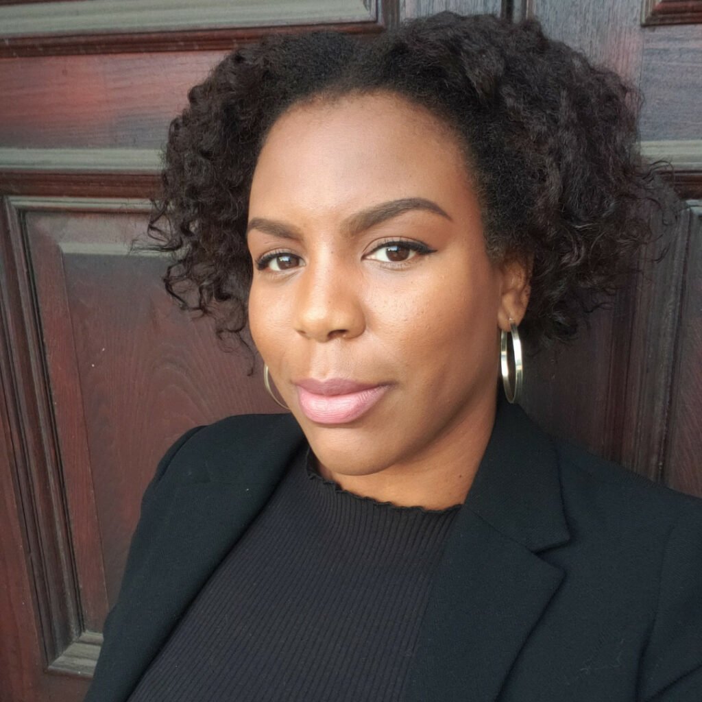 Headshot of Nola Sterling, she is wearing a black suit jacket and silver earrings 