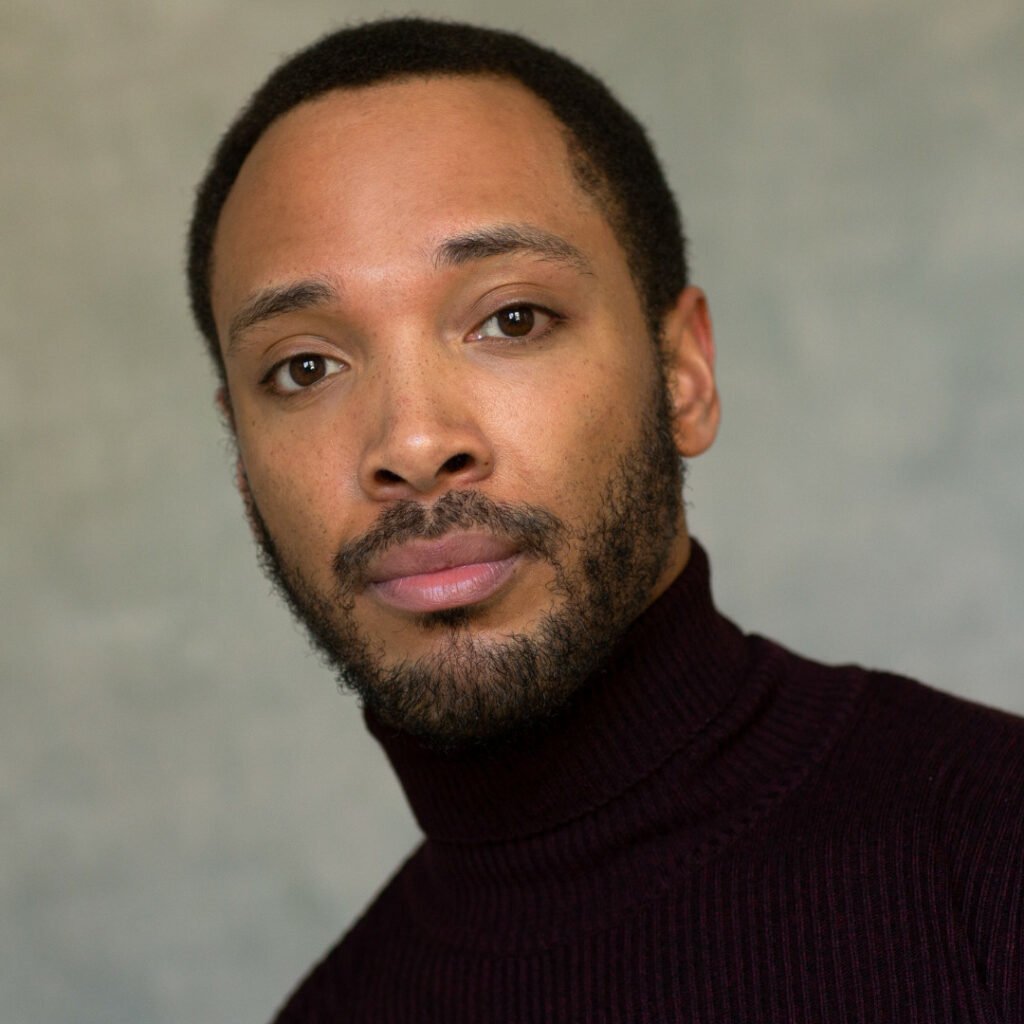 Headshot of Linden Walcott-Burton, he is wearing a black turtle-neck jumper