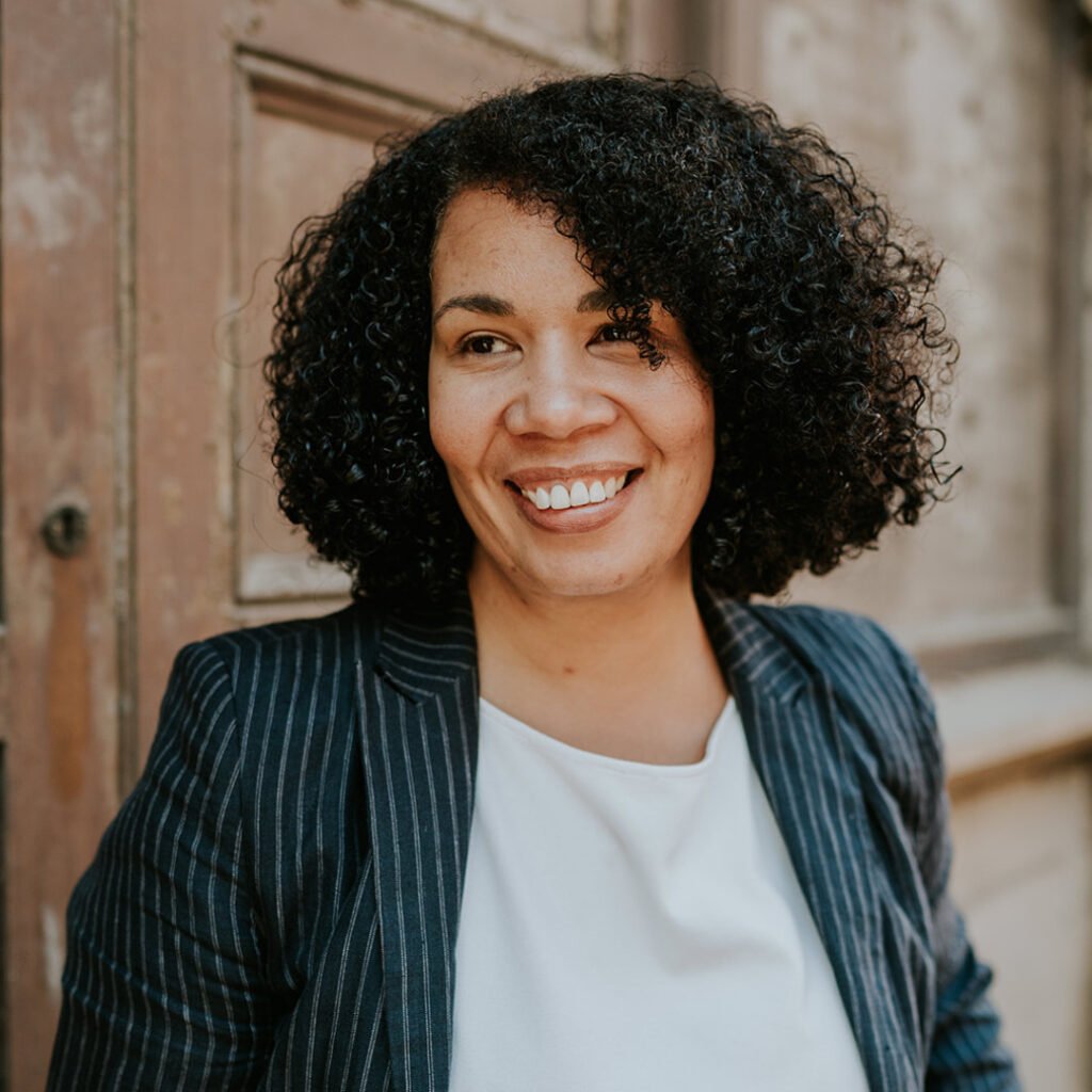 Headshot of Shonagh Reid, she is stood outside wearing a pin striped jacket and smiling.