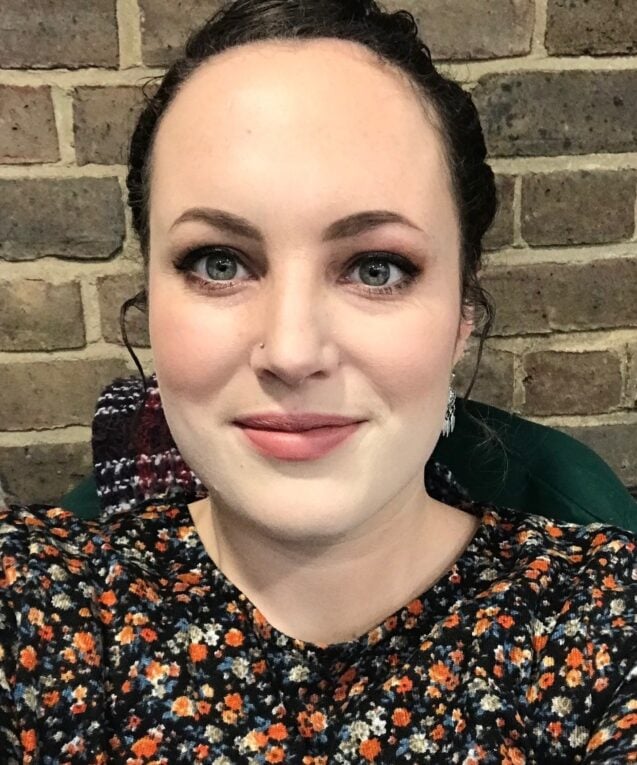 Headshot of Kate Davey; a white woman in her mid-thirties with dark hair. Photo taken against a brick wall back drop.