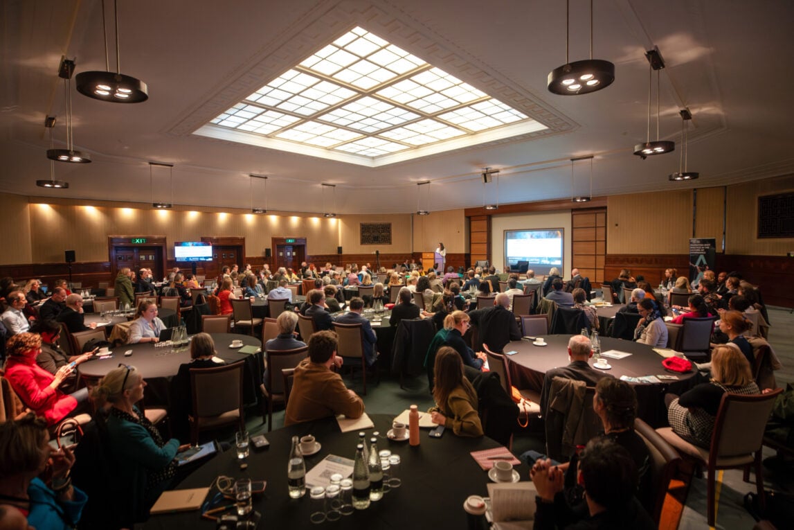 A group of people sitting at tables listening to a keynote at Governance Now 2024